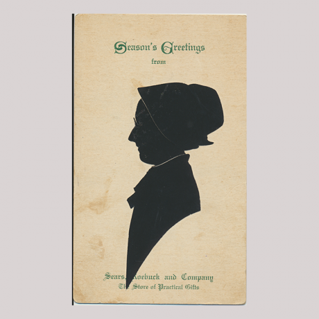 
        Front of silhouette, with woman looking left, wearing a bonnet and glasses. With inscription, Season's Greetings...